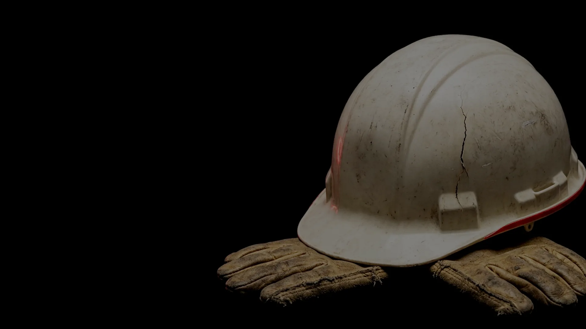 Casco de obra blanco, rajado, sobre guantes de trabajo